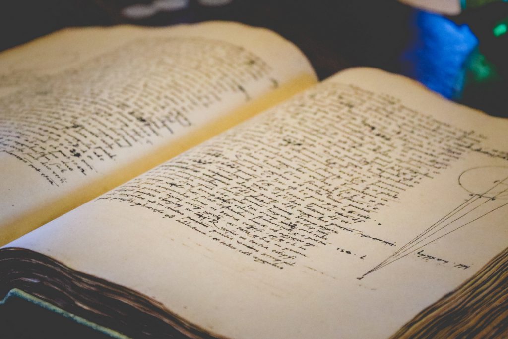 Otwarte, stare książki z ręcznie zapisanymi stronami.