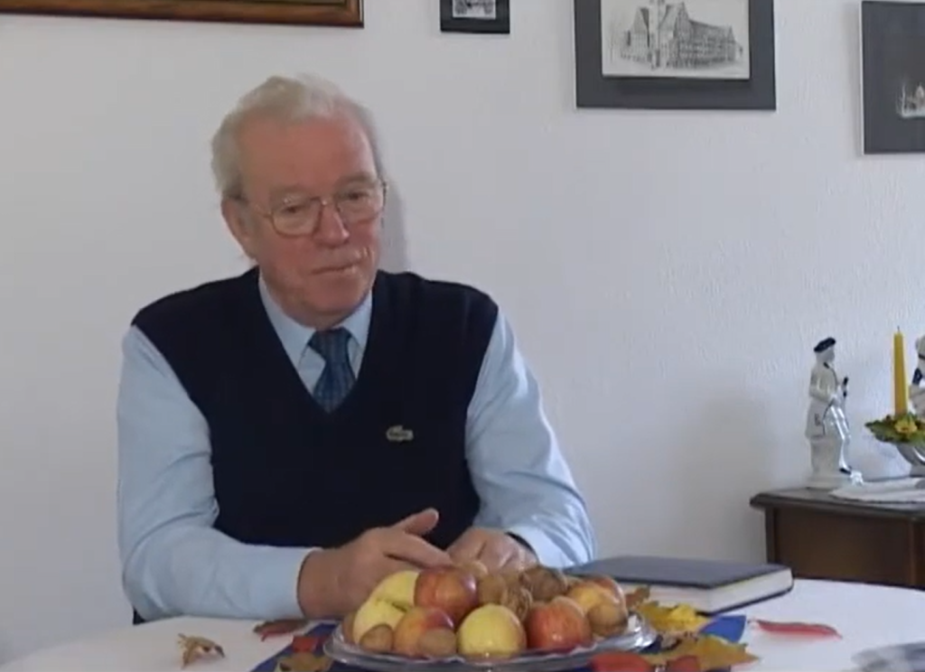 Mężczyzna siedzący przy stole z owocami.