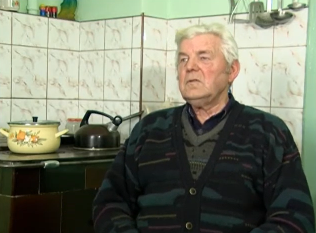 Starszy mężczyzna siedzi w kuchni.