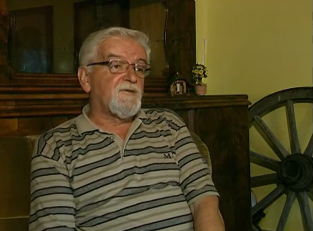 Mężczyzna w paskowanej koszulce siedzi w pomieszczeniu