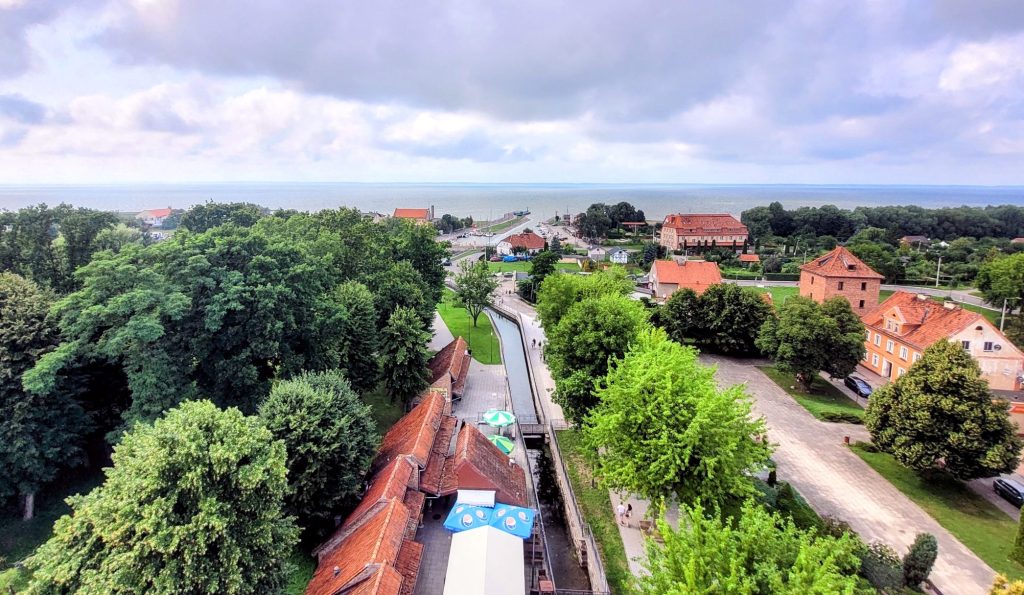 Widok na miasto z drzewami i morzem w tle.