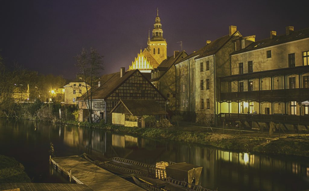 Widok na zabytkowe budynki przy rzece nocą.