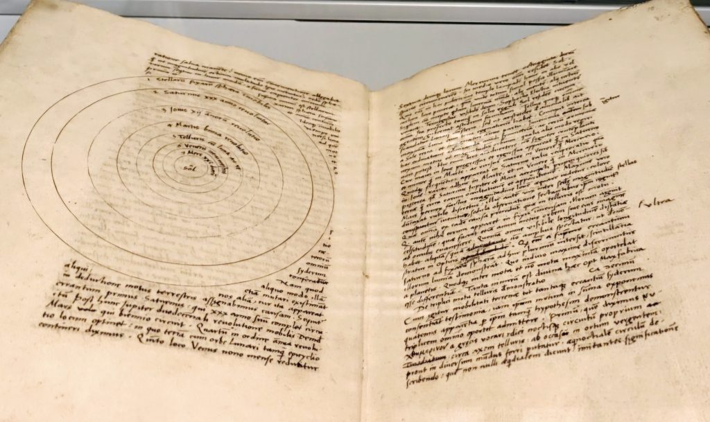 Starożytna książka z diagramem planetarnym i tekstem ręcznym.