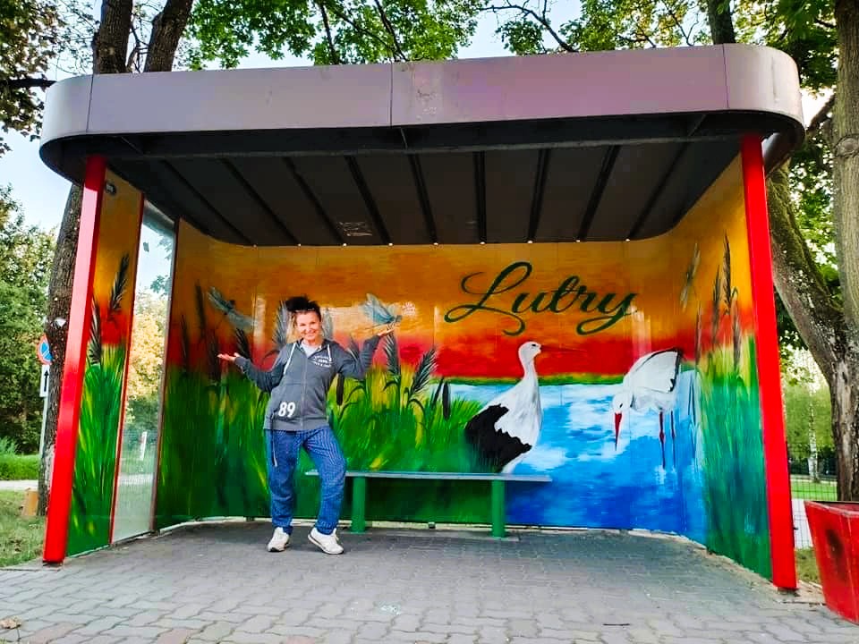 Osoba w autobusie z kolorowym muralem.