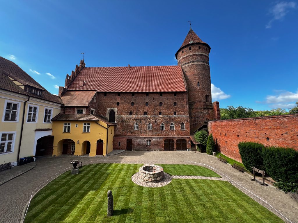 Widok na zamek z dziedzińcem i zieloną trawą.