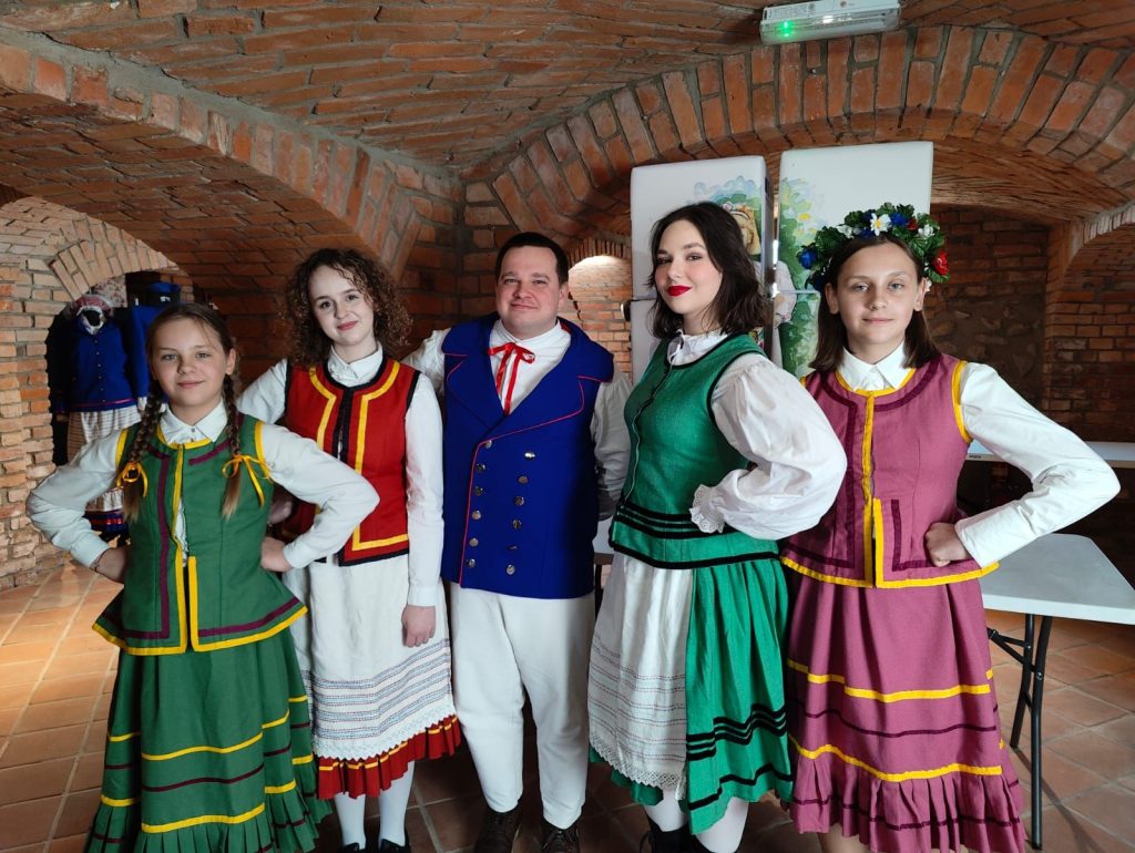 Grupa osób w tradycyjnych strojach ludowych.