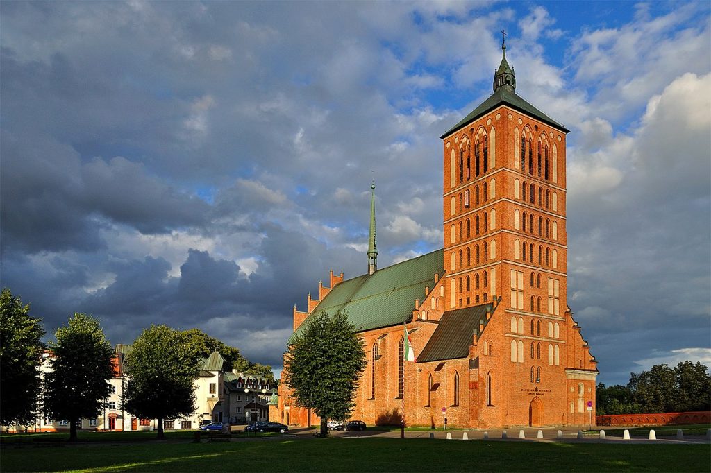 Ceglana świątynia z wieżą na tle chmur.