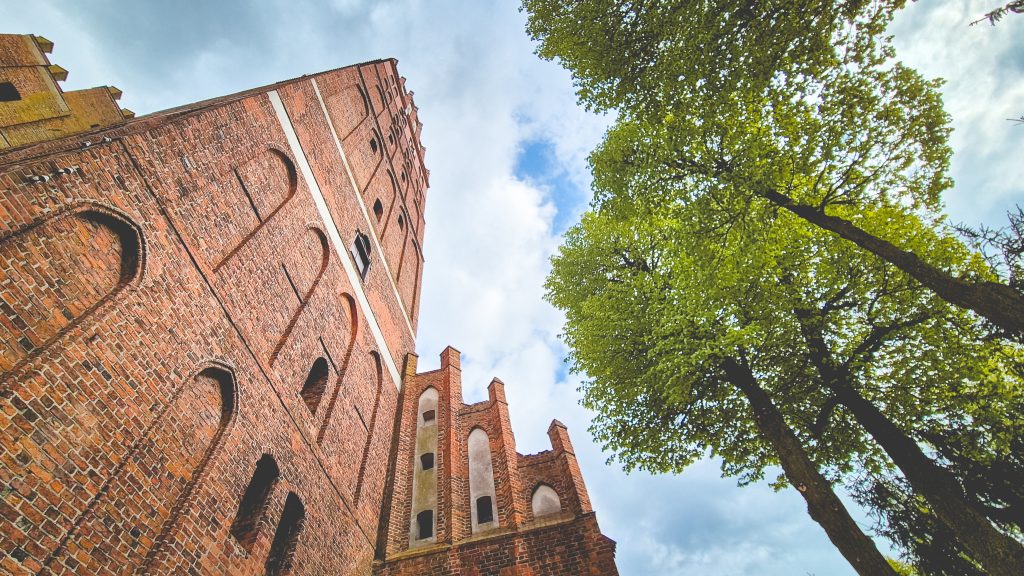 Wysoka ceglana wieża z zielonymi drzewami