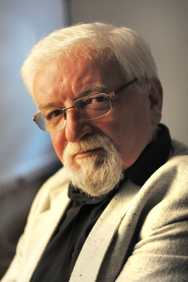 Portret starszego mężczyzny z brodą i okularami.