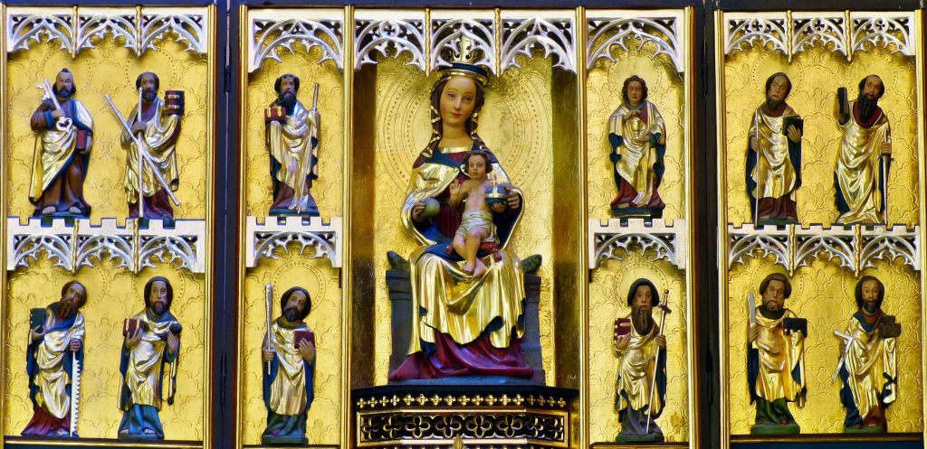 Rzeźbiona scena religijna z Maryją i figurami świętych.