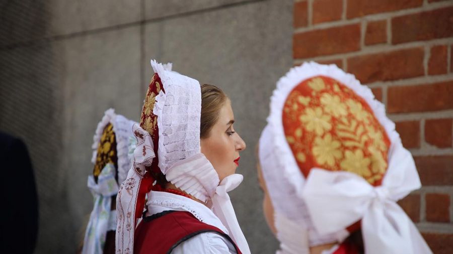 Trzy kobiety w tradycyjnych strojach ludowych z ozdobnymi chustami.