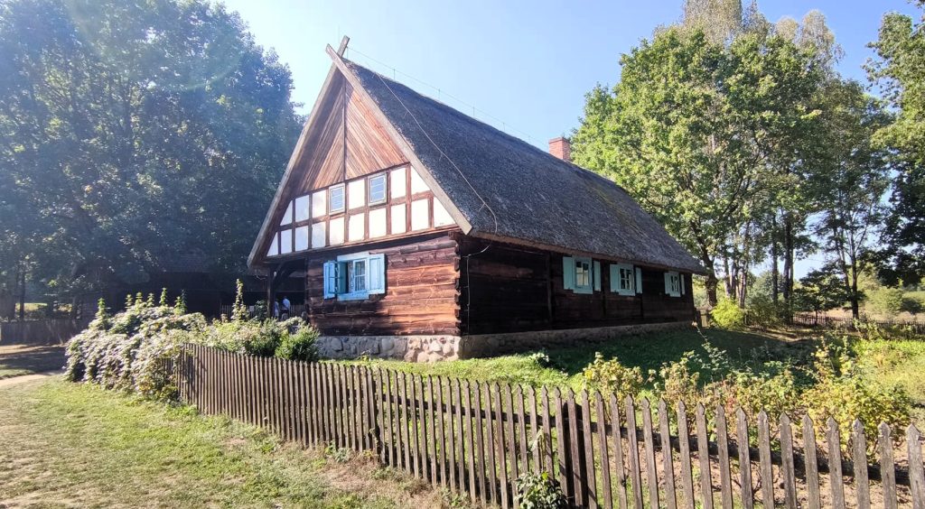 Drewniany dom z trawiastym dachem w otoczeniu drzew.